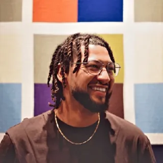 Erwin Lejeune, smiling, with glasses and braids